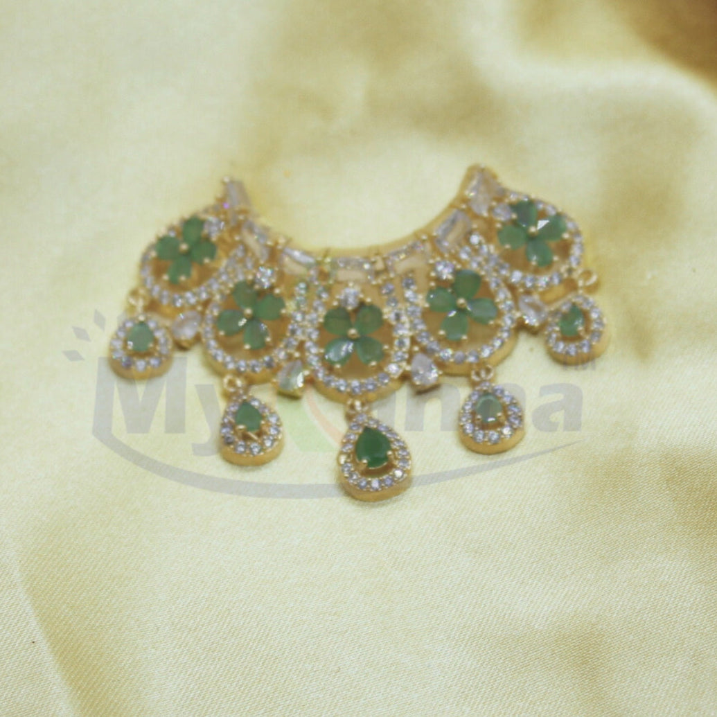 Decorative necklace with green stones and gold accents on a beige fabric background